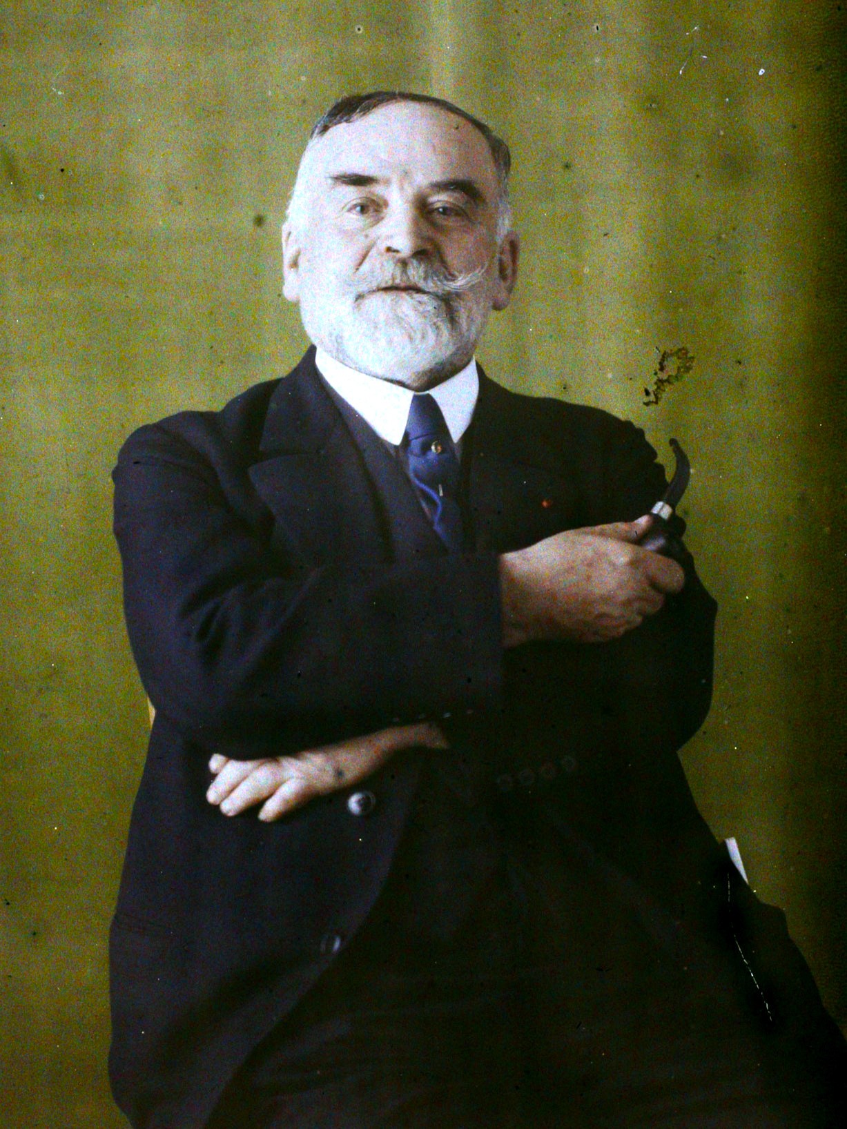 A colorized 1929 portrait photograph of Marcellin Boule, an elderly bearded man in a dark suit holding a pipe